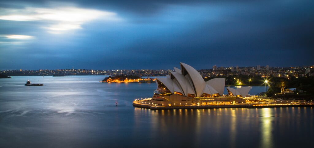 Sydney ooperimaja tuledes õhtuse sadama ja kuuvalguse taustal